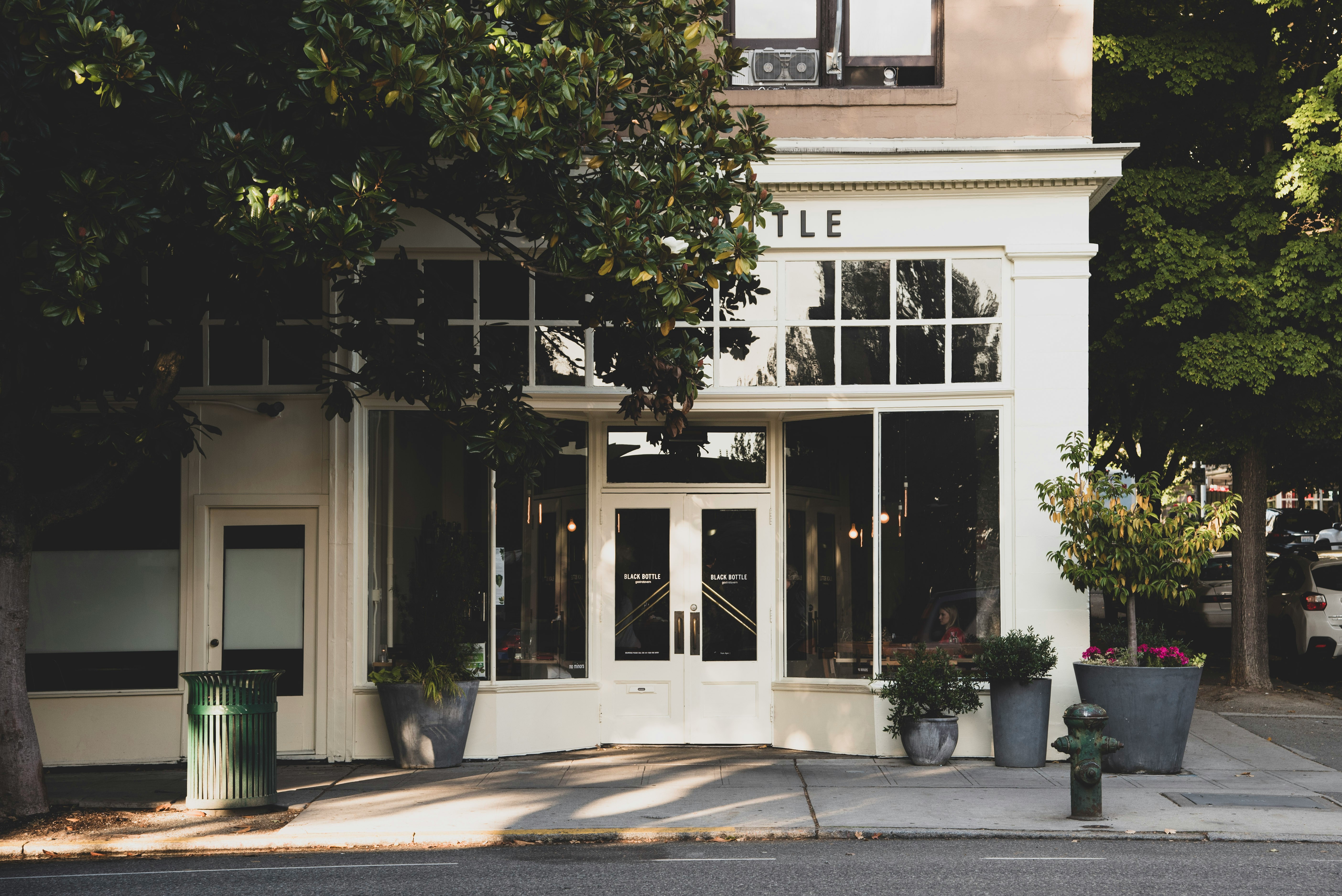 A storefront commercial building on a tree-lined street.